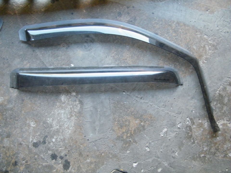 two dark-colored window visors on a concrete surface