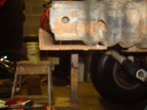 1995 Ford Bronco - The photo shows a close-up of a rusty metal beam and a tire, likely a part of a vehicle's undercarriage.