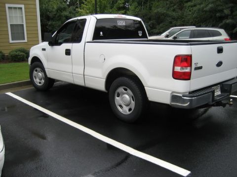 2004 Ford F-150 - A white 2004 Ford F-150 pickup truck is parked in a lot, seen from the rear three-quarter angle.