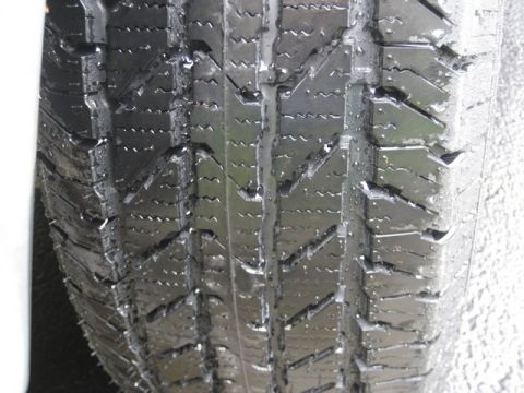 2004 Ford F-150 - A close-up view of a tire's tread pattern, showing water droplets on its surface.