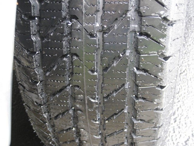 Close-up of a wet tire tread with the "SUPERMOTORS.NET" watermark visible