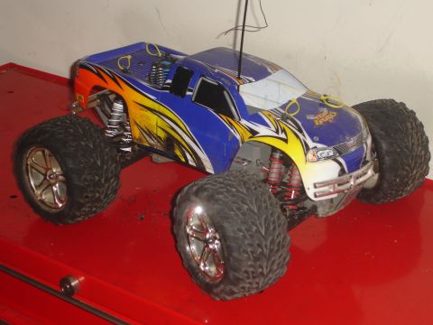 1989 Ford Bronco - A blue and yellow remote control monster truck sits on a red surface, its large tires prominent.