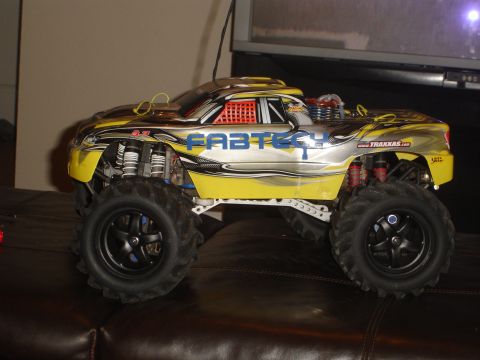 1989 Ford Bronco - A remote control monster truck with large tires and a yellow and silver body is parked on a leather couch.