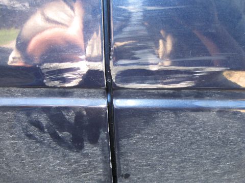 2005 Ford F-150 - Scratches and scuffs mar the paint on the seam between two dark blue truck doors.