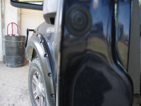 2005 Ford F-150 - Detail of a truck door jamb and fender flare, with a trash can in the background.