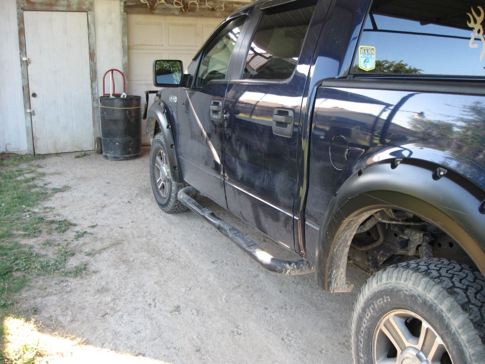 Dark blue pickup truck side view, showing fender flares, running boards, and tinted windows