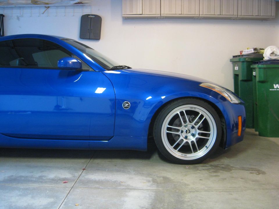 Blue sports coupe side view with silver alloy wheel parked in a garage