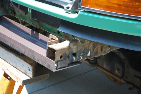 1996 Ford Bronco - Custom metal fabrication being added to the front bumper frame of a green vehicle, supported by jack stands.