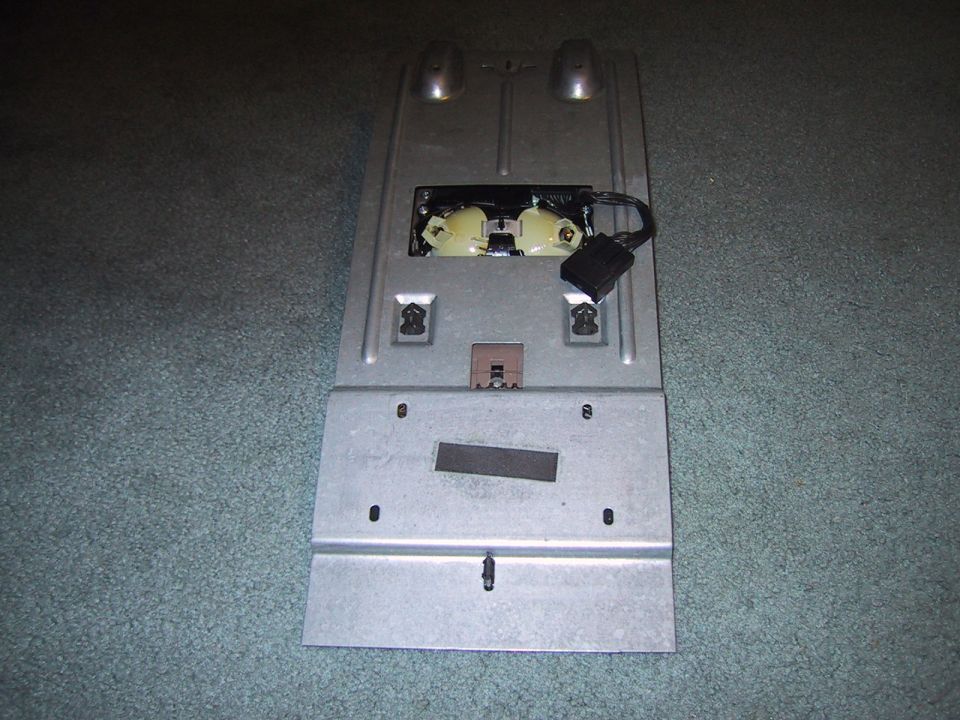 Photo of an overhead console mounting bracket lying on carpet