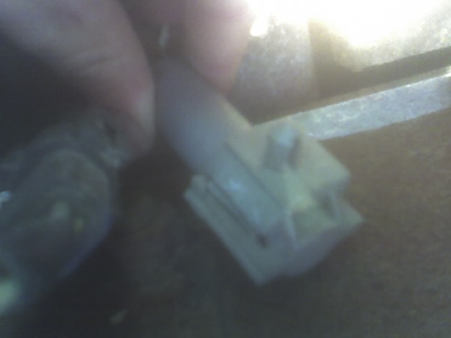 Close-up of a hand holding a white electrical connector with multiple pins