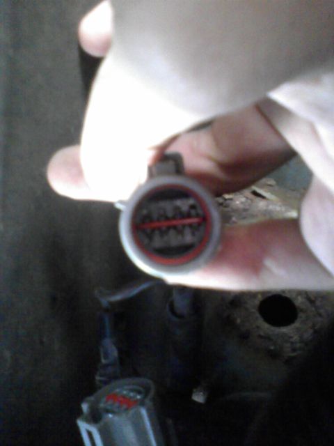 1991 Ford Bronco - A hand holds a gray electrical connector with red trim and visible pins.