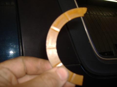 1988 Ford Bronco - A hand holds up a broken tan/amber plastic C-shaped ring with segmented facets around its circumference, snapped clean at both ends. It is…