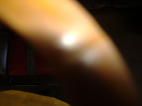 1988 Ford Bronco - Badly out-of-focus, mostly dark frame dominated by a blurred tan object lit by a small light source, with an indistinct red panel in the le…