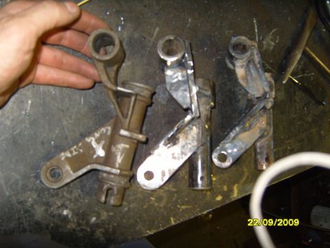 1989 Ford Bronco - Metal bracket parts laid out on a workbench, possibly for repair or modification.