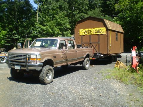 1979 Ford Bronco - A brown Ford F-250 pickup truck tows a shed marked 'WIDE LOAD'.