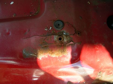 1984 Ford Bronco - Close-up of a rusted metal floor pan showing damage and bolt holes.