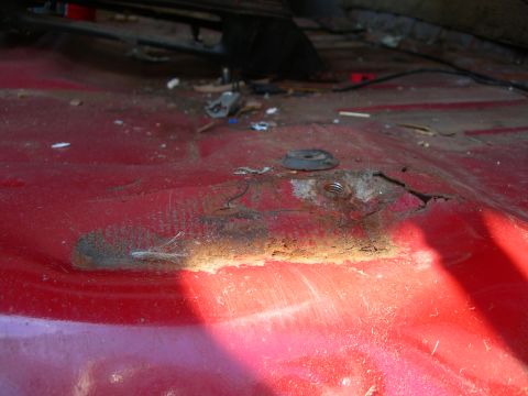 1984 Ford Bronco - Close-up of a corroded vehicle floor pan, showing damage and hardware.
