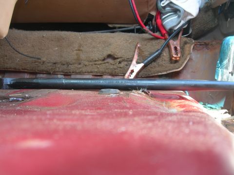 1984 Ford Bronco - Jumper cables are connected to a battery inside a vehicle, with a tool nearby that warns against using it as a hammer.