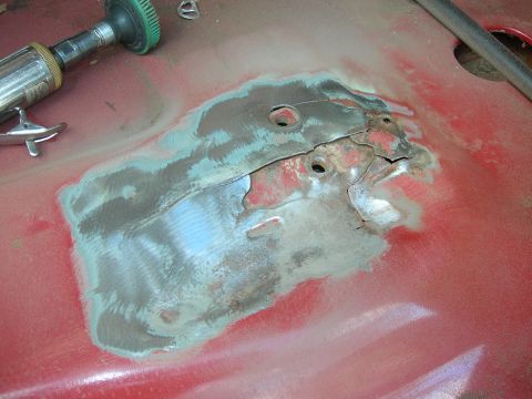 1984 Ford Bronco - Auto body panel shows rust damage and cracks, being prepped for repair with a grinder.