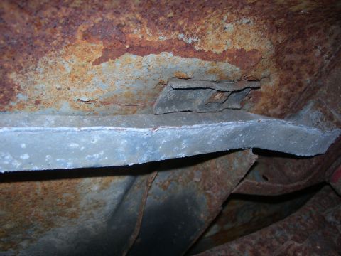 1984 Ford Bronco - Close-up view of heavily rusted undercarriage components, indicating significant wear and tear.