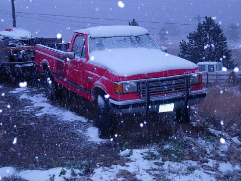 1989 Ford F-250 - Red 1989 Ford F-250 pickup truck sits in the snow with another vehicle visible in the background.