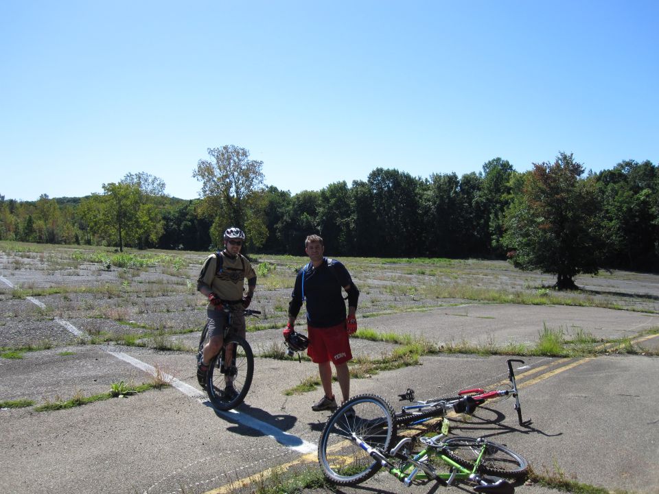 Two guys with mountain bikes in an empty lot