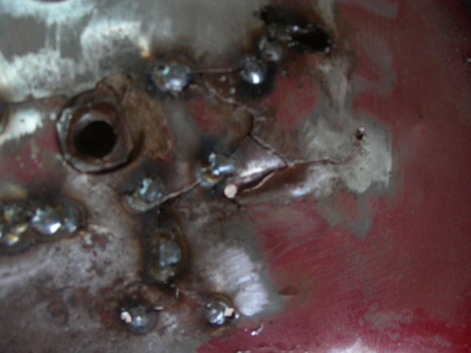 Close-up of cracked and welded metal with a circular hole