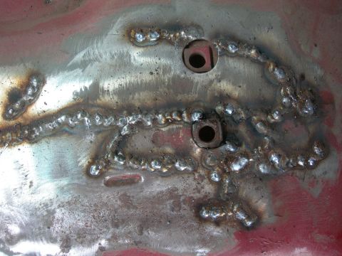 1984 Ford Bronco - This is a close-up of a metal surface with visible welds and holes, likely a repair or modification.