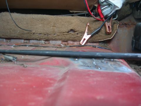 1984 Ford Bronco - Jumper cables are connected to a battery inside a vehicle's interior.