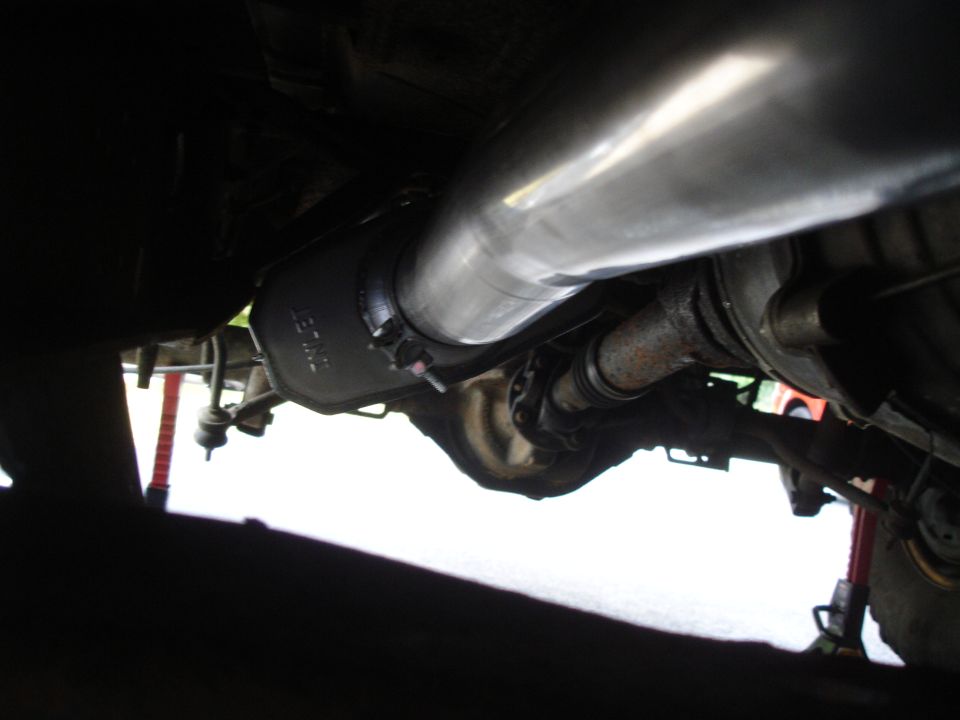 Underside view of a vehicle's exhaust system, showing the muffler and driveshaft