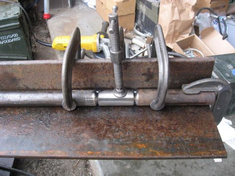 1990 Ford F-250 - Metal components are secured with clamps and a central bolt, ready for welding. A yellow power grinder is visible in the background.