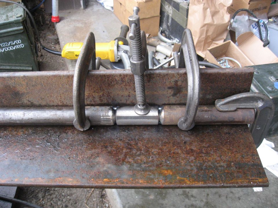 Metal pieces clamped for welding with a yellow grinder in background