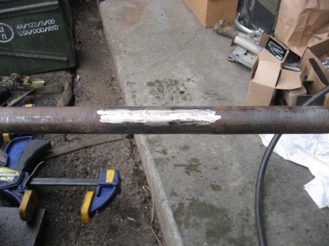 1990 Ford F-250 - A metal pipe is clamped and marked with white paint, with various boxes and parts in the background.