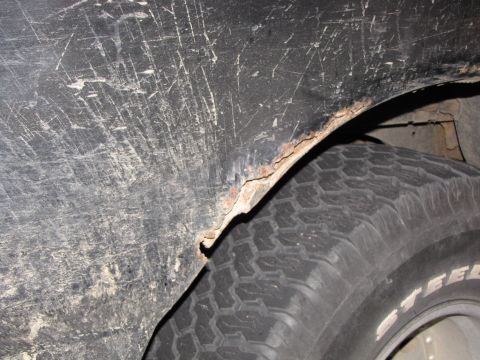 1993 Ford Bronco - Rusted wheel well arch and tire detail, showing wear and tear.