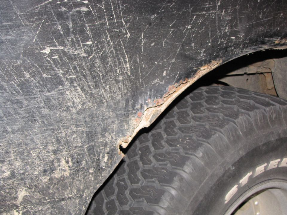 Close-up of a rusted wheel well arch and tire on a vehicle