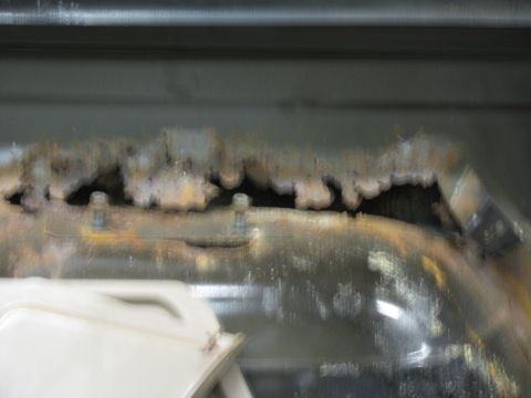 1993 Ford Bronco - A close-up view shows significant rust damage on a metal panel, with a white object visible in the foreground.
