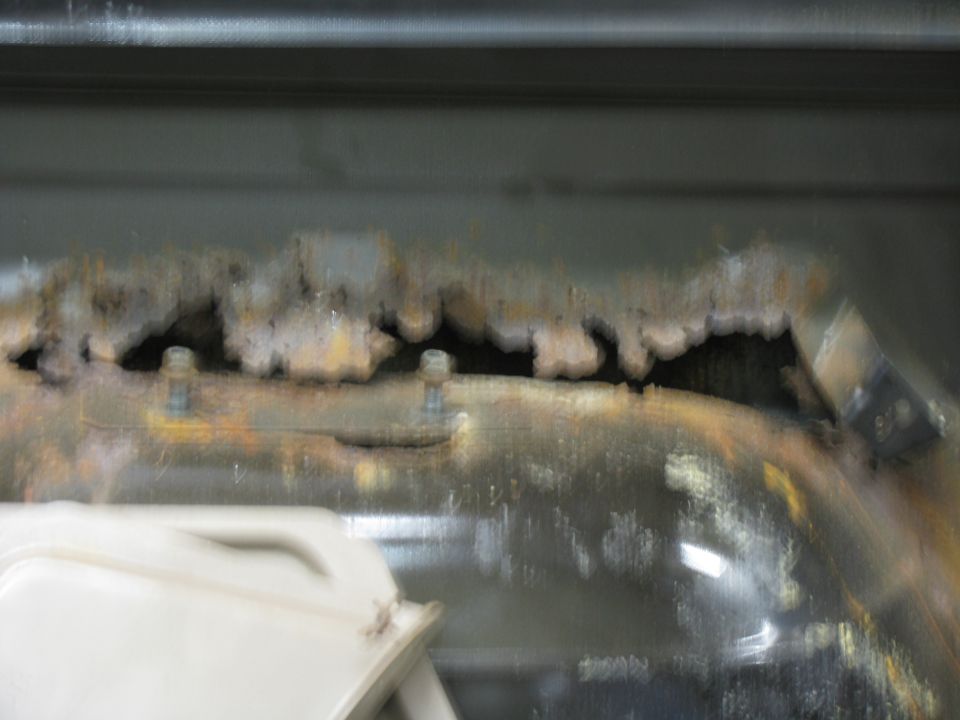 rusted metal panel with bolts, part of a white object below