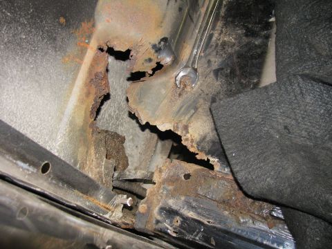 1993 Ford Bronco - Severe rust damage is visible on the vehicle's frame, with a wrench resting on the corroded metal.