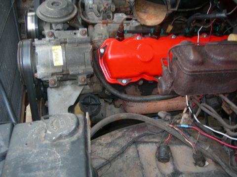 1984 Ford Bronco - Close-up view of an engine bay bright red valve covers and an air conditioning compressor.