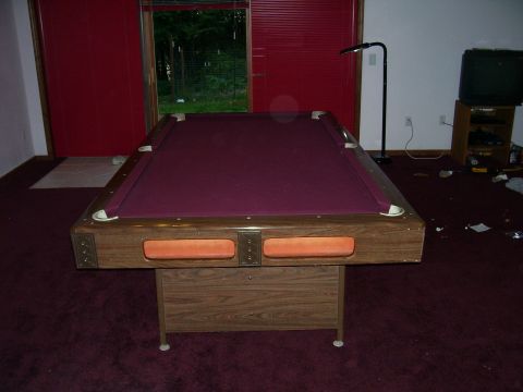 1991 Ford Bronco - A pool table with a purple felt surface and wooden frame is set up in a room with red doors and a television in the background.