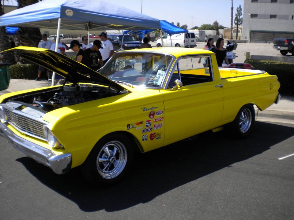 Yellow classic Ranchero with open hood and decals at a car show