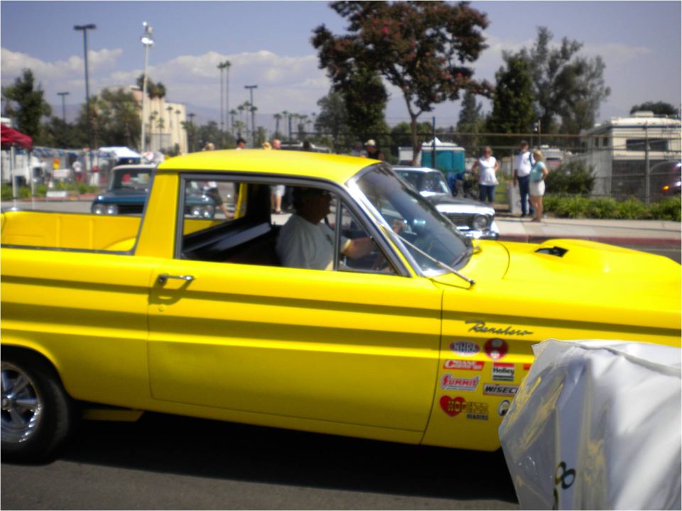 Yellow Ranchero car-pickup with driver at an outdoor car show