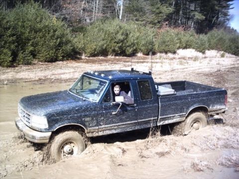 1989 Ford F-150 - Driver looks out of a 1989 Ford F-150 stuck deep in mud during an off-road excursion.