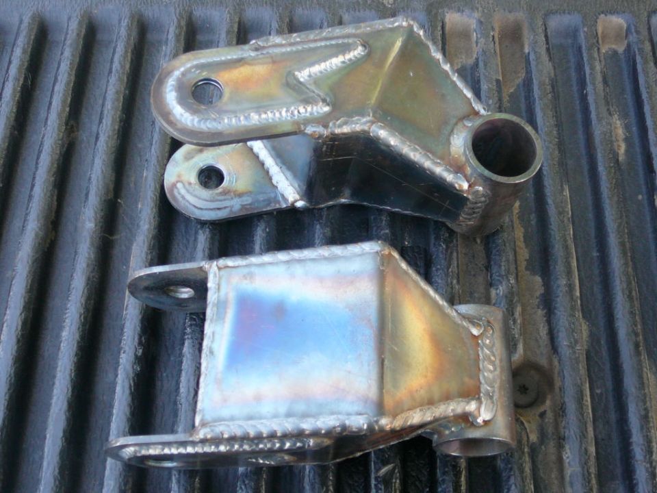 Two custom fabricated metal suspension parts with visible welds