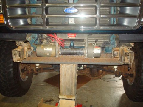 1995 Ford Bronco - The front of a teal 1992 Ford Bronco is shown, equipped with a winch and raised on a lift.