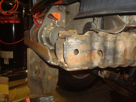 1995 Ford Bronco - Winch installation on a vehicle frame, showing rusty metal and wooden supports.