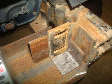1995 Ford Bronco - Close-up view of heavily rusted metal brackets attached to a vehicle's frame, showing signs of modification.
