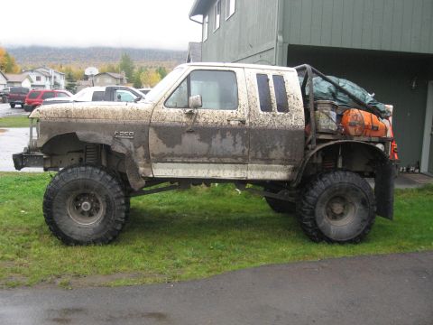 1990 Ford F-250 - This heavily modified 1990 Ford F-250 pickup truck is covered in mud, suggesting recent off-road use.