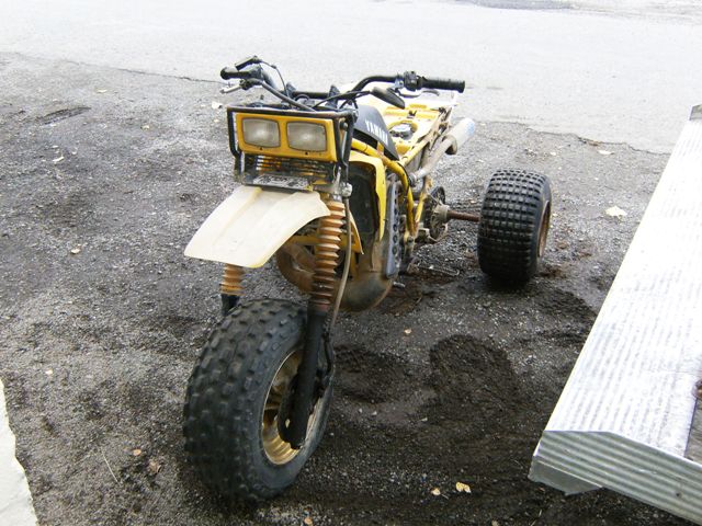 Yellow three-wheeled ATV with dual headlights and large tires