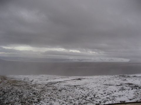 1990 Ford F-250 - A vast, snow-covered landscape under a heavy, cloudy sky with mountains on the horizon.